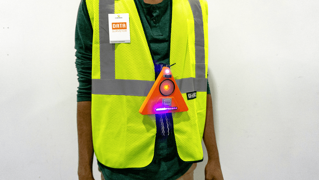 Person wearing a high visability vest with an orange triangular shaped device attached to the middle