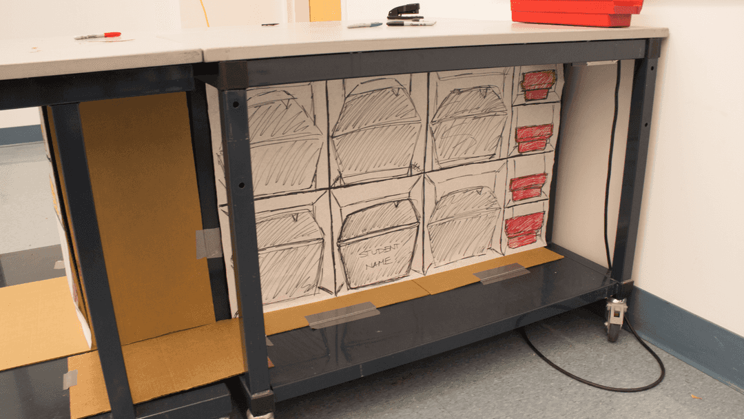 Cardboard prototype of shelves located underneath a table