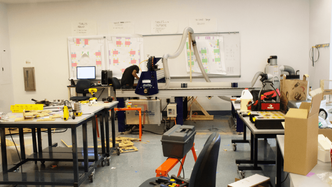 A person using a CNC router in the middle of a classroom