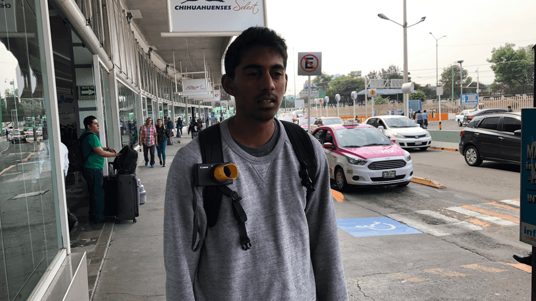 Person wearing a backpack on the street with a camera mounted to the shoulder strap