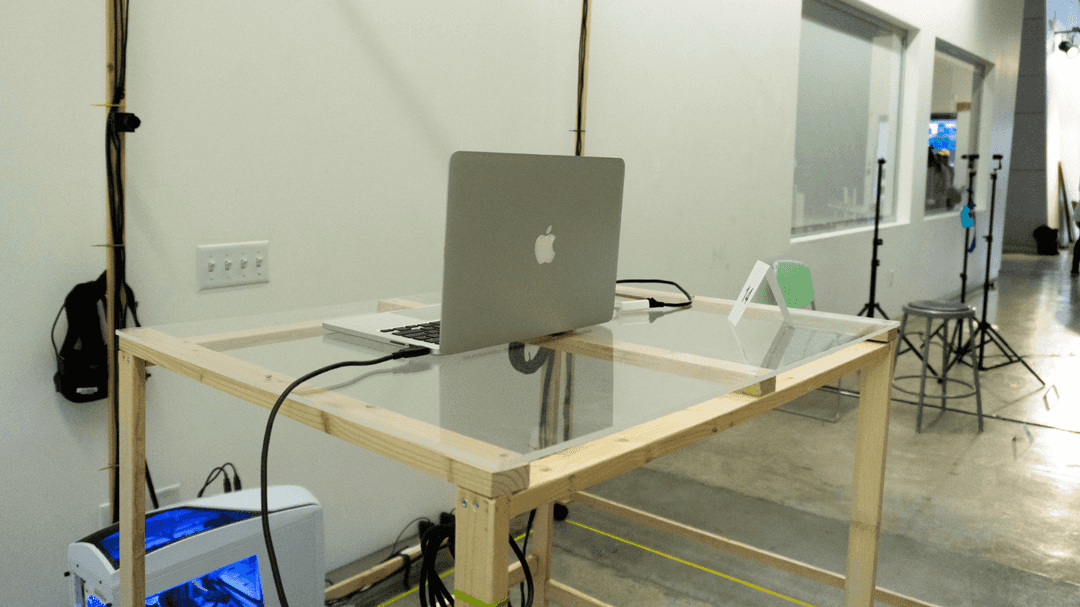 Laptop sitting on a standing height table in the middle of a room-sized wooden frame