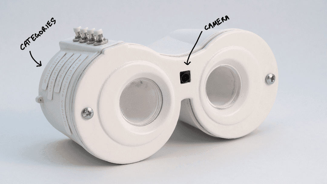 A data collection device in the shape of binoculars with a camera and buttons along the top
