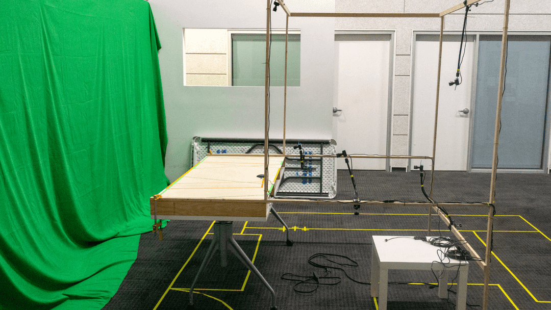 An empty table surrounded by a wooden frame, with webcams mounted to it